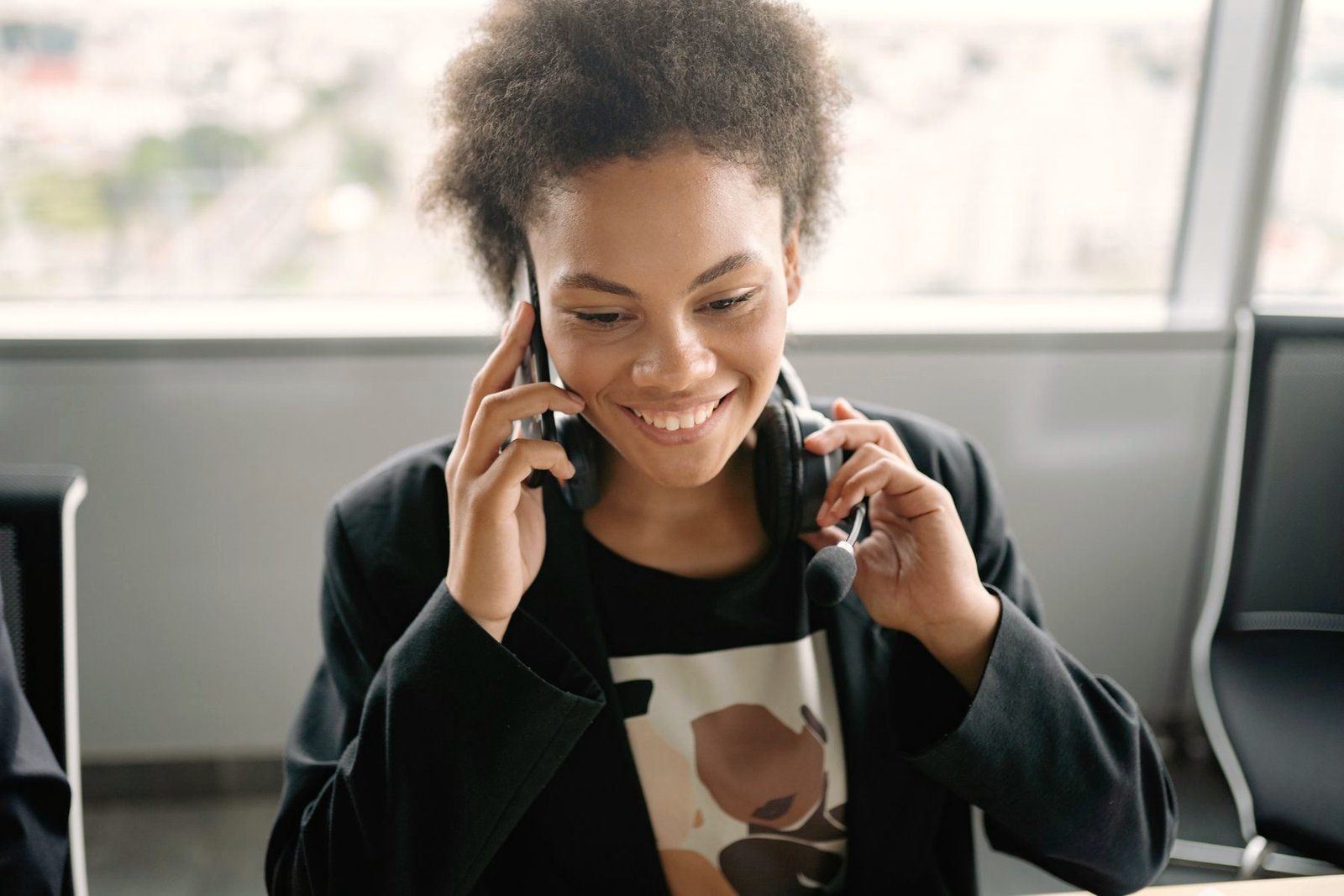 An operator smiling while taking a call near a bright window