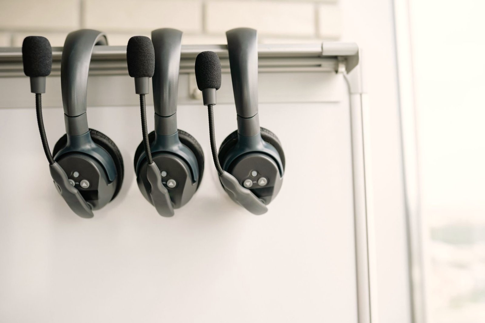 Three telephone headsets hanging ready on a hook