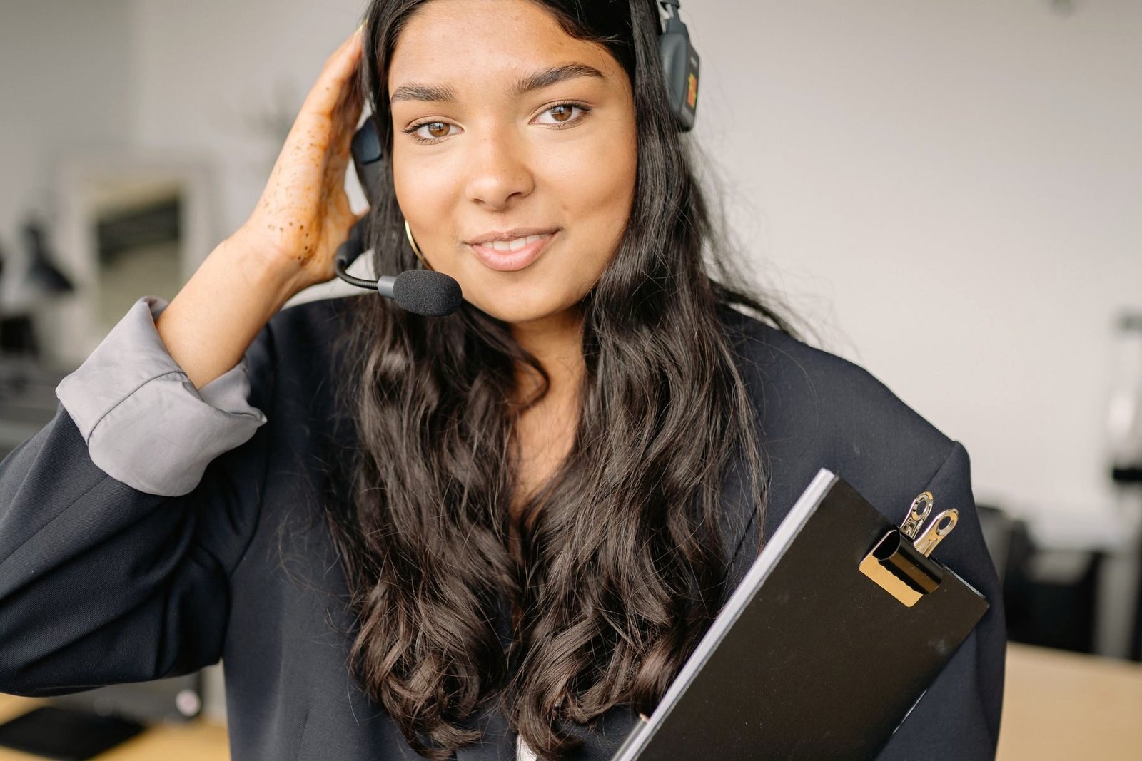 An operator adjusting her headset while holding a clipboard
