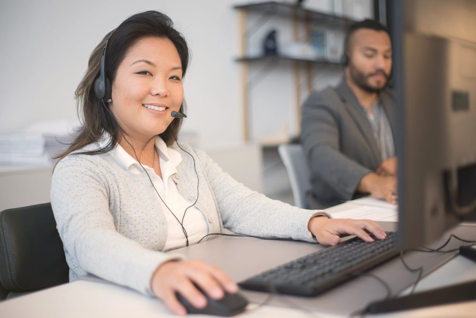 Two operators working at computers in a bright office